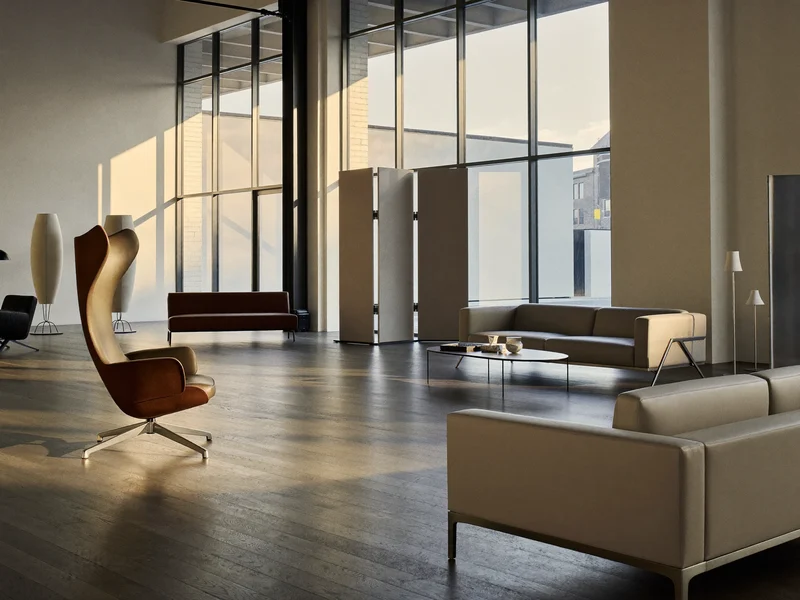 Prázdný světlý showroom s několika kusy nábytku na dřevěné podlaze.
